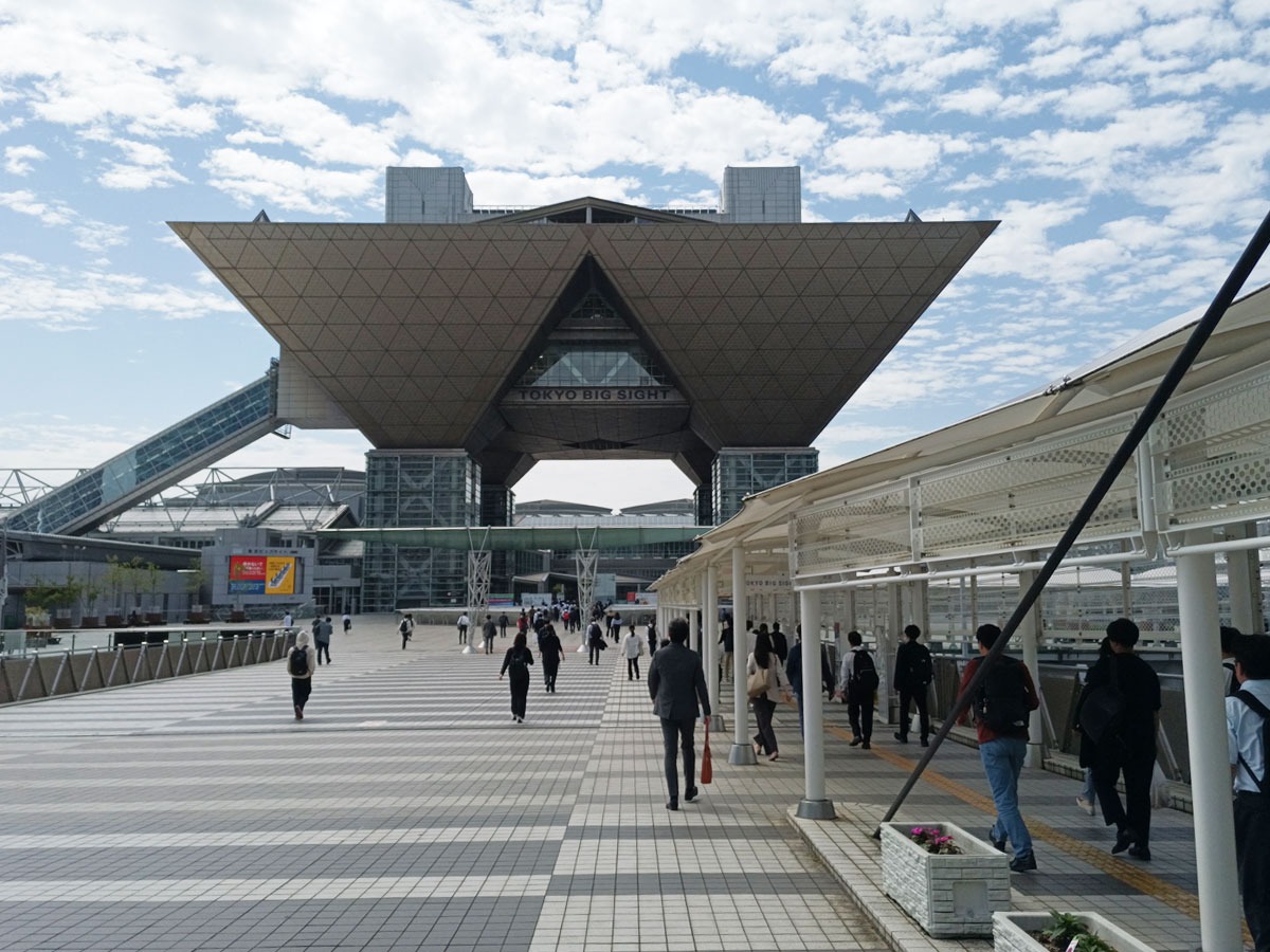 写真：東京ビッグサイト正面の遠景。たくさんのビジネスパーソンがビッグサイトに向かって歩いている